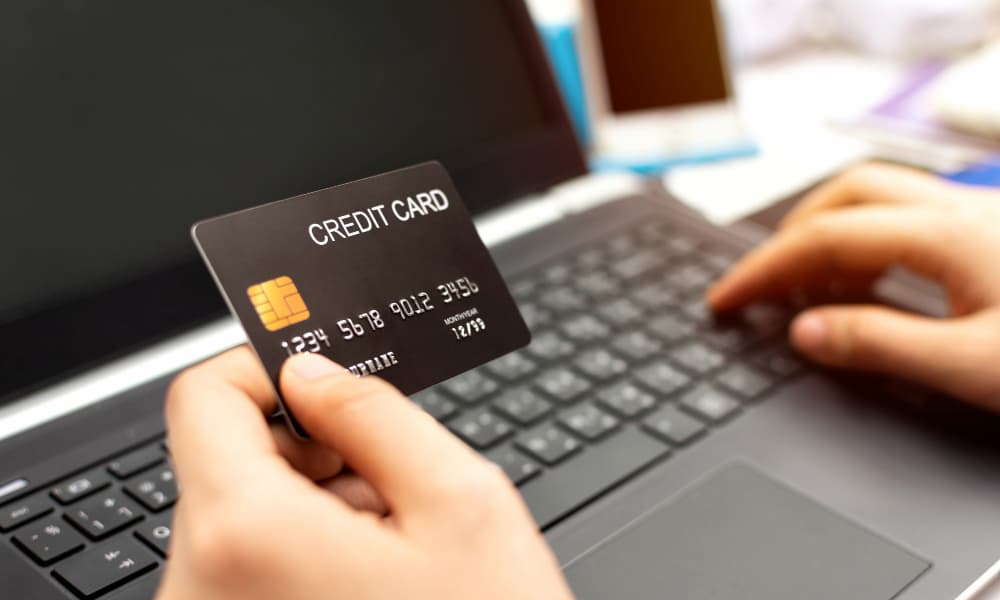 Person using a credit card while working on a laptop