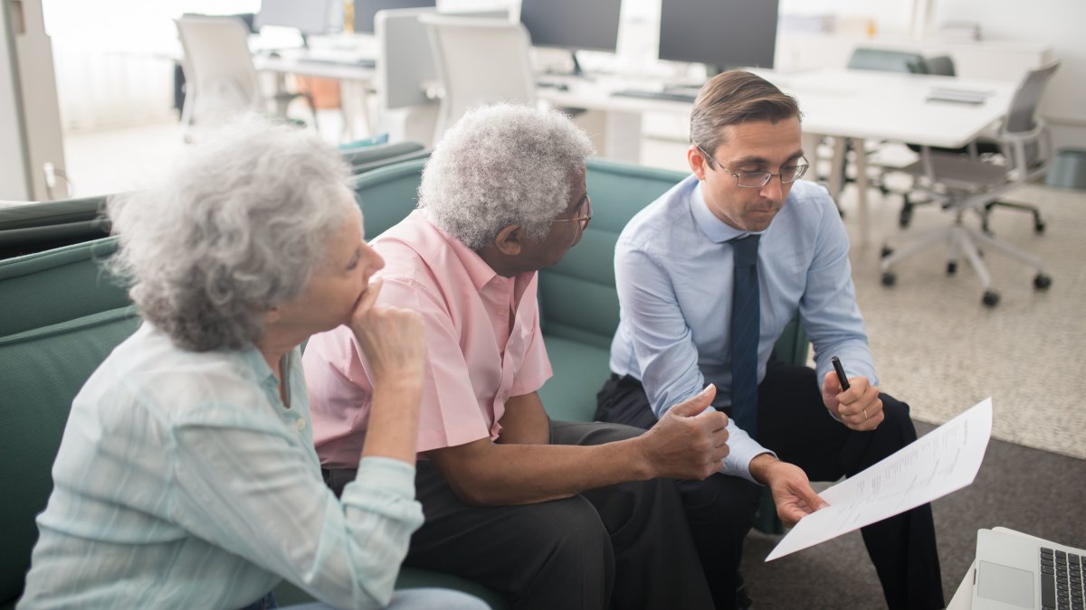Financial professional consults with elderly clients in an office setting with paperwork visible