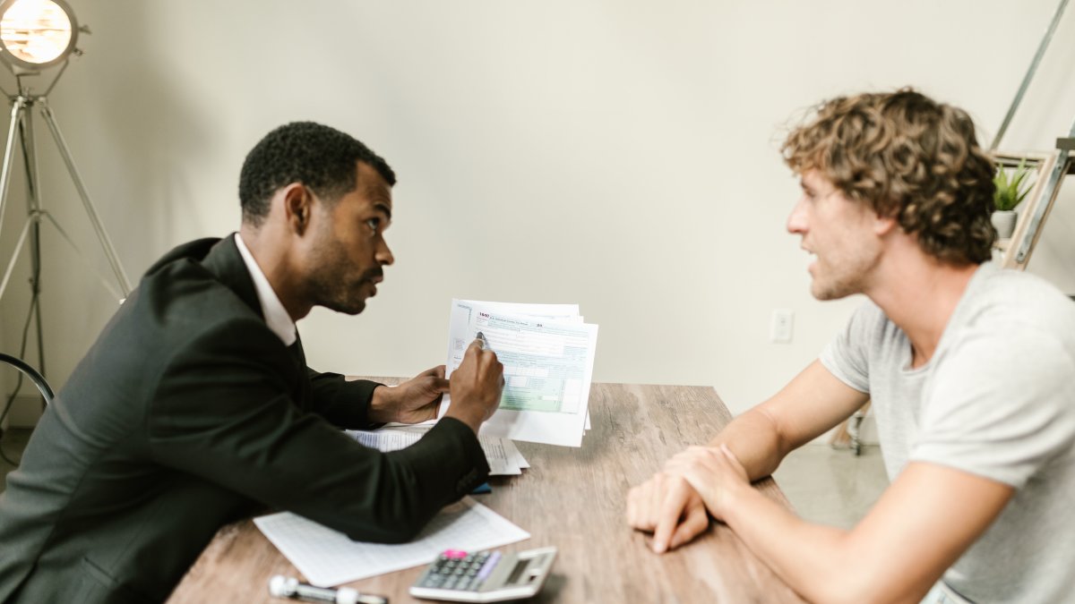Financial advisor discussing paperwork with a client at a desk in a modern office