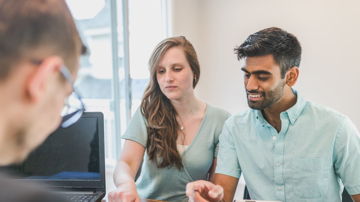 Young couple consulting with a financial advisor using a calculator and documents in a bright office setting