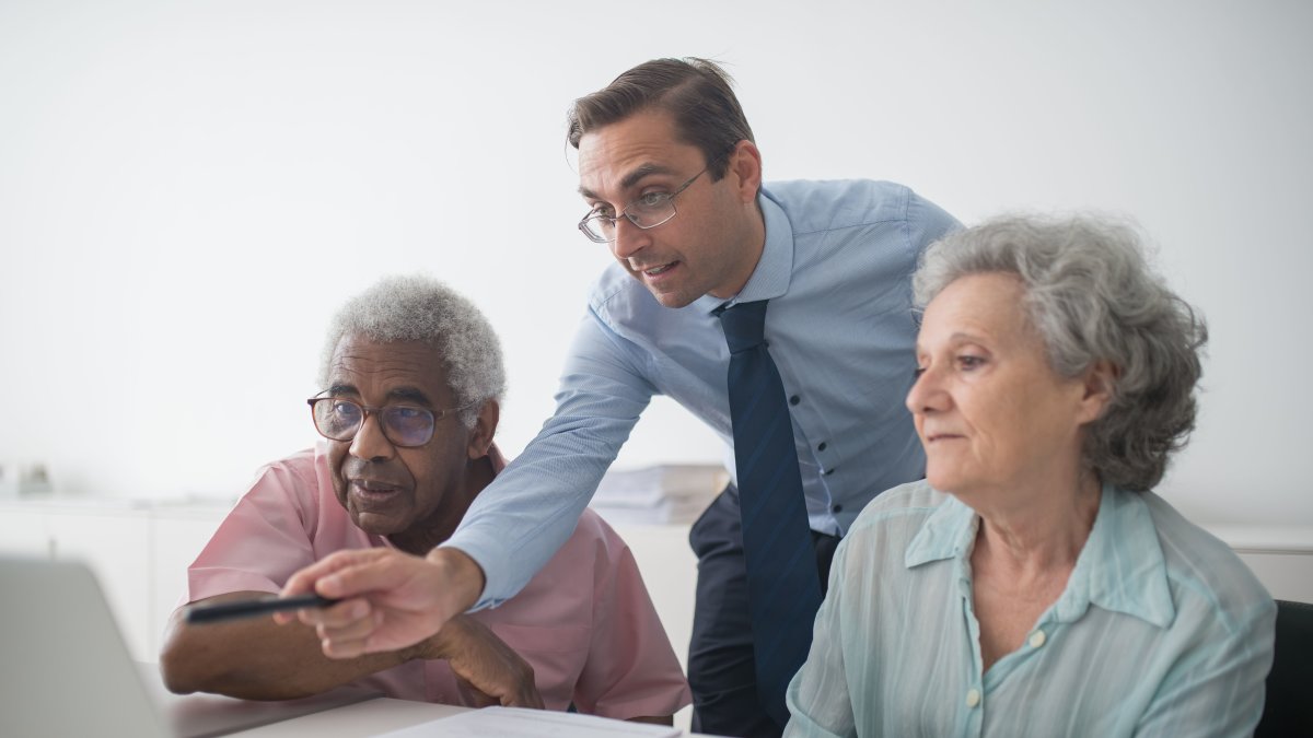 Financial advisor explaining financial options to senior clients using a laptop for illustration