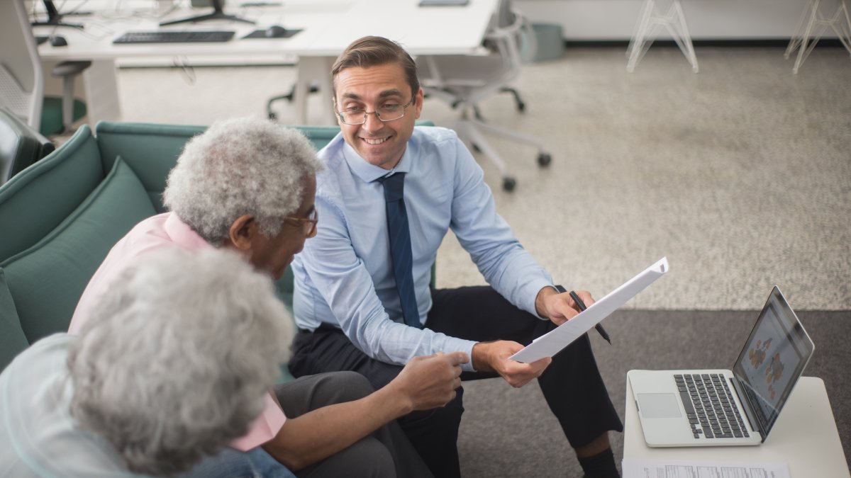 Financial consultant discussing plans with senior clients using documents and laptop